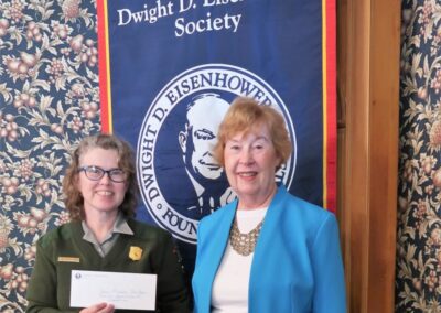 Executive Director Carol Hegeman presents Eisenhower National Historic Site Manager Jana Friesen McCabe with a check for $537 in funds donated at the Eisenhower Society booth at World War II Weekend. Funds will be dedicated to next year's World War II event.
